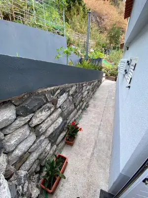 a stone retaining wall with two plants on the sidewalk at Lovely newly refurbished, 1 bedroom top floor apartment with sea views, fast WI-FI CABLE TV and Netflix in Ribeira Brava
