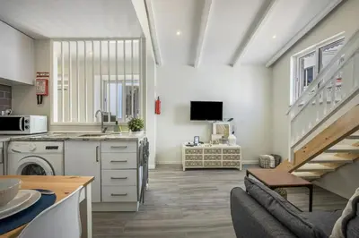 a living room with a kitchen and a staircase at Casa da Villa in Vila do Bispo