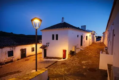 a street light next to a white building at night at Casa Amado, Aldeia da Pedralva in Vila do Bispo