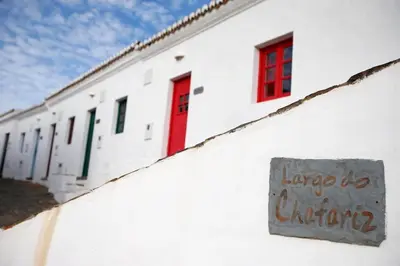 a white building with red windows and a sign on it at Casa Amado, Aldeia da Pedralva in Vila do Bispo