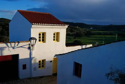 a white building with a red roof and yellow windows at Casa Amado, Aldeia da Pedralva in Vila do Bispo