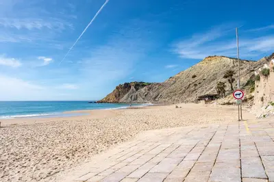 a sandy beach with a sign in front of the ocean at Vista Mar - Burgau in Burgau