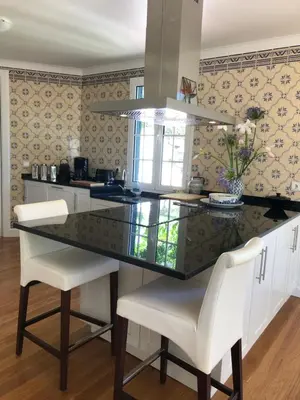 a kitchen with a glass counter top and white chairs at Villa-sleeps2-garden-private park in Camacha