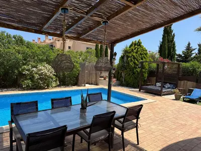 a patio with a table and chairs next to a swimming pool at Spacious 3 bedroom villa with pool in Luz