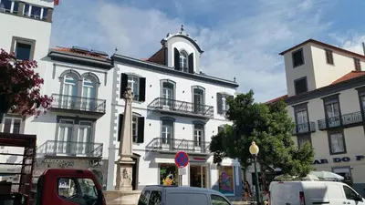 a white building with a clock tower on a street at Edificio Charles 101 in Funchal