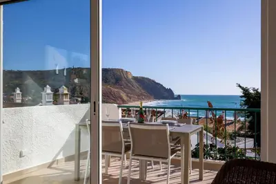 a balcony with a table and chairs and a view of the ocean at Casa Rujo - Waterside Village House in Luz