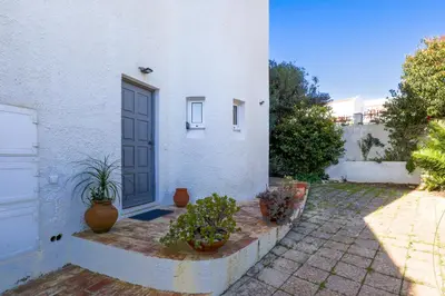 a white house with potted plants in front of a door at Casa Rujo - Waterside Village House in Luz