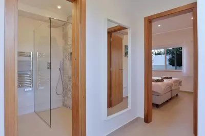 a bedroom with a glass shower and a bed at Casa Rujo - Waterside Village House in Luz