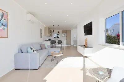 a white living room with a couch and a table at Casa Rujo - Waterside Village House in Luz