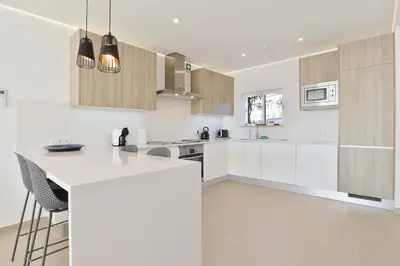 a kitchen with white cabinets and a white counter top at Casa Rujo - Waterside Village House in Luz