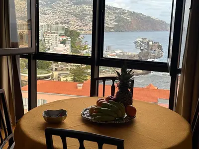a table with a bowl of fruit and a window at Madeira Inn Group in Funchal
