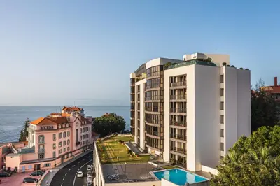 a view of a building with the ocean in the background at Madeira Inn Group in Funchal