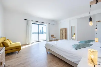 a white bedroom with a large bed and a yellow couch at Fortaleza sea view Villa Miramar - Apartment with private pool in Budens