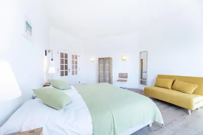 a white bedroom with a large bed and a yellow couch at Fortaleza sea view Villa Miramar - Apartment with private pool in Budens