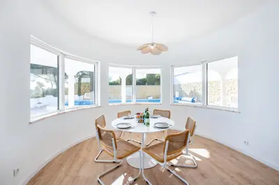 a dining room with a table and chairs and windows at Fortaleza sea view Villa Miramar - Apartment with private pool in Budens