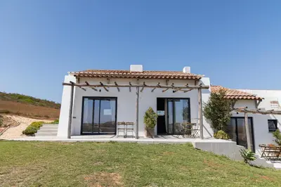a small white house with some tables and chairs at Casa Nook Sagres in Vila do Bispo