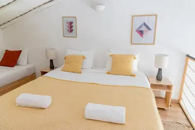 a bedroom with a large white bed with yellow pillows at Casa Nook Sagres in Vila do Bispo