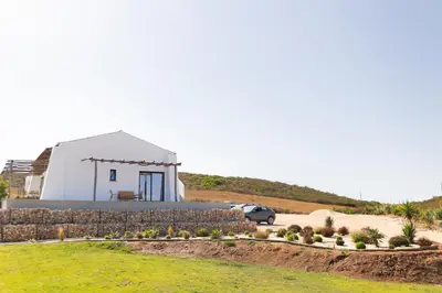 a white house with a car parked in front of it at Casa Nook Sagres in Vila do Bispo