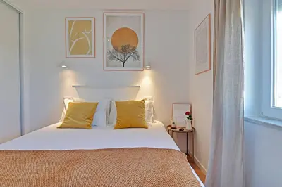 a bedroom with a bed with white sheets and yellow pillows at Sea Salt, Sagres Apartment in Sagres