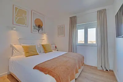 a bedroom with a large white bed with yellow pillows at Sea Salt, Sagres Apartment in Sagres