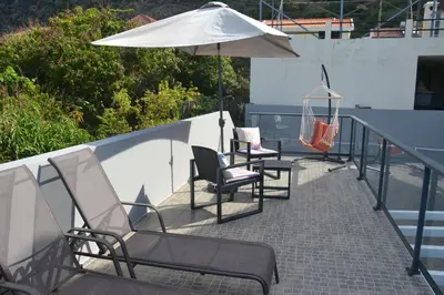 a group of chairs and an umbrella on a balcony at Casa d' Avó Zeza in Jardim do Mar