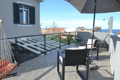 a balcony with two chairs and an umbrella at Casa d' Avó Zeza in Jardim do Mar