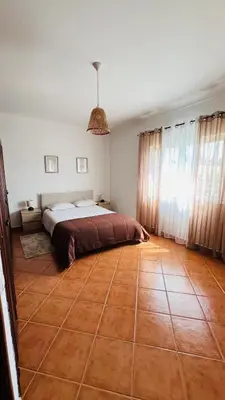 a bedroom with a bed and a tiled floor at Quinta dos Moledros in Figueira