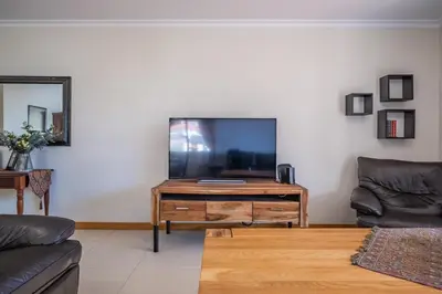 a living room with a flat screen tv on a wooden table at Casa grata in Arco da Calheta
