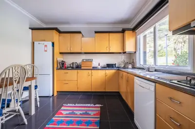 a kitchen with wooden cabinets and a white refrigerator at Casa grata in Arco da Calheta