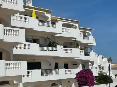 a white apartment building with white balconies and purple flowers at Superbe appartement vue sur mer à 180° Luz in Luz