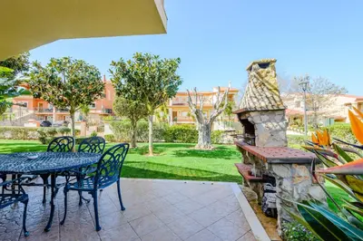 a patio with a table and chairs and a stone fireplace at Casa Sunny Days - Boavista Resort in Lagos