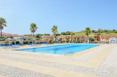 a swimming pool at a resort with blue chairs and palm trees at Casa Sunny Days - Boavista Resort in Lagos