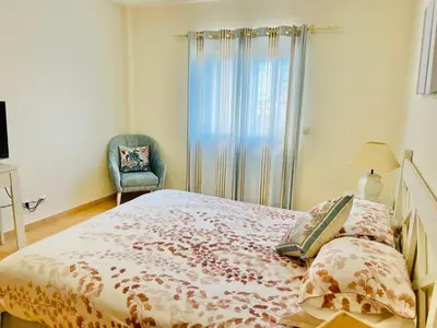 a bedroom with a bed and a chair and a window at Estrela da Praia da Luz - 2 Bedroom Sea View Apartment in Luz