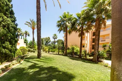 a lawn with palm trees in front of a building at Estrela da Praia da Luz - 2 Bedroom Sea View Apartment in Luz