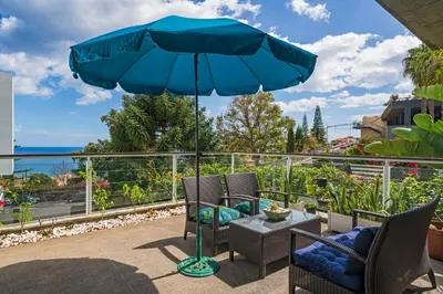 a patio with a table and chairs and an umbrella at Barreiros II by An Island Apart in Funchal