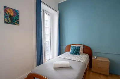 a bedroom with a bed with a cat laying on it at Madeirarooms in Funchal