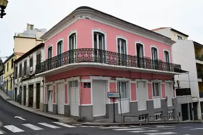 a pink building with a balcony on a street at Madeirarooms in Funchal