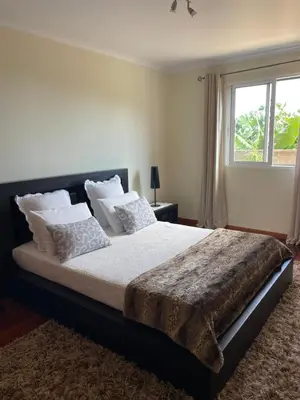 a bedroom with a large bed with a window at Cantinho da Té in Câmara de Lobos