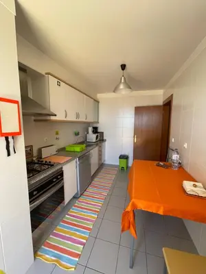 a kitchen with an orange table in the middle of it at Cantinho da Té in Câmara de Lobos