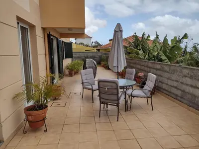 a patio with a table and chairs and an umbrella at Cantinho da Té in Câmara de Lobos
