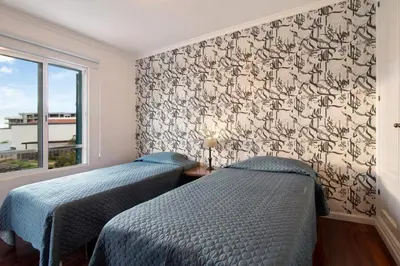 a bedroom with two beds and a wall with a wallpaper at Seaside Escape in Funchal