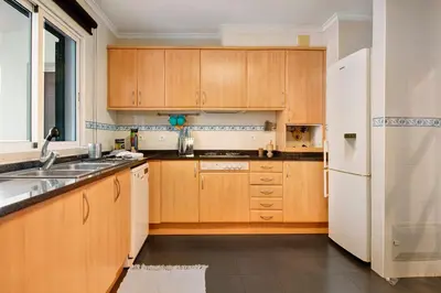 a kitchen with wooden cabinets and a white refrigerator at Seaside Escape in Funchal