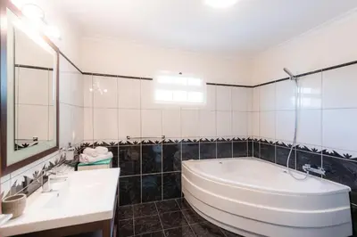 a white bathroom with a tub and a sink at Sunnyside Villa in Arco da Calheta