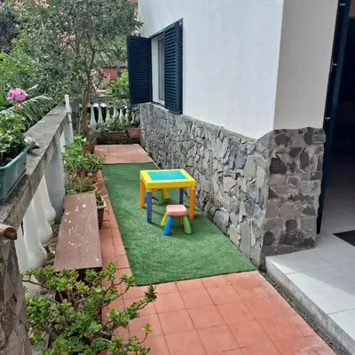 a colorful table and stool on a lawn in front of a house at Chalé Seixal - Sea View in Seixal