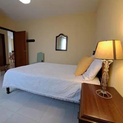a bedroom with a bed and a lamp on a table at Chalé Seixal - Sea View in Seixal