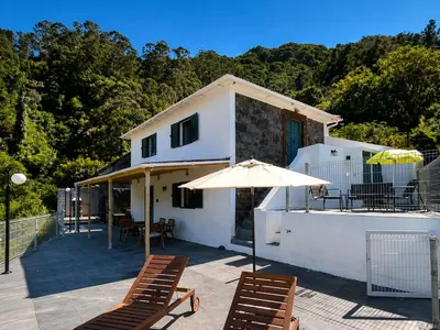 a patio with two chairs and an umbrella at VViP Vila Madeira in São Vicente