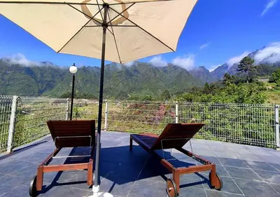 two chairs and an umbrella on a patio at VViP Vila Madeira in São Vicente