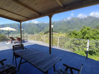a porch with a picnic table and a view of mountains at VViP Vila Madeira in São Vicente
