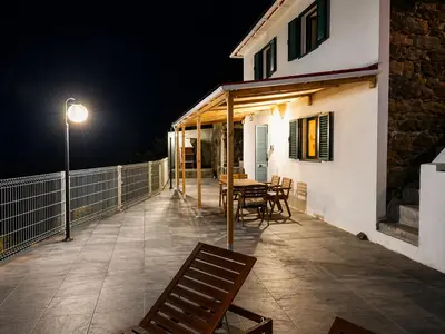 a patio with a table and chairs at night at VViP Vila Madeira in São Vicente
