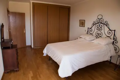 a bedroom with a white bed and a wooden floor at Casa Da Atalaia in Caniço